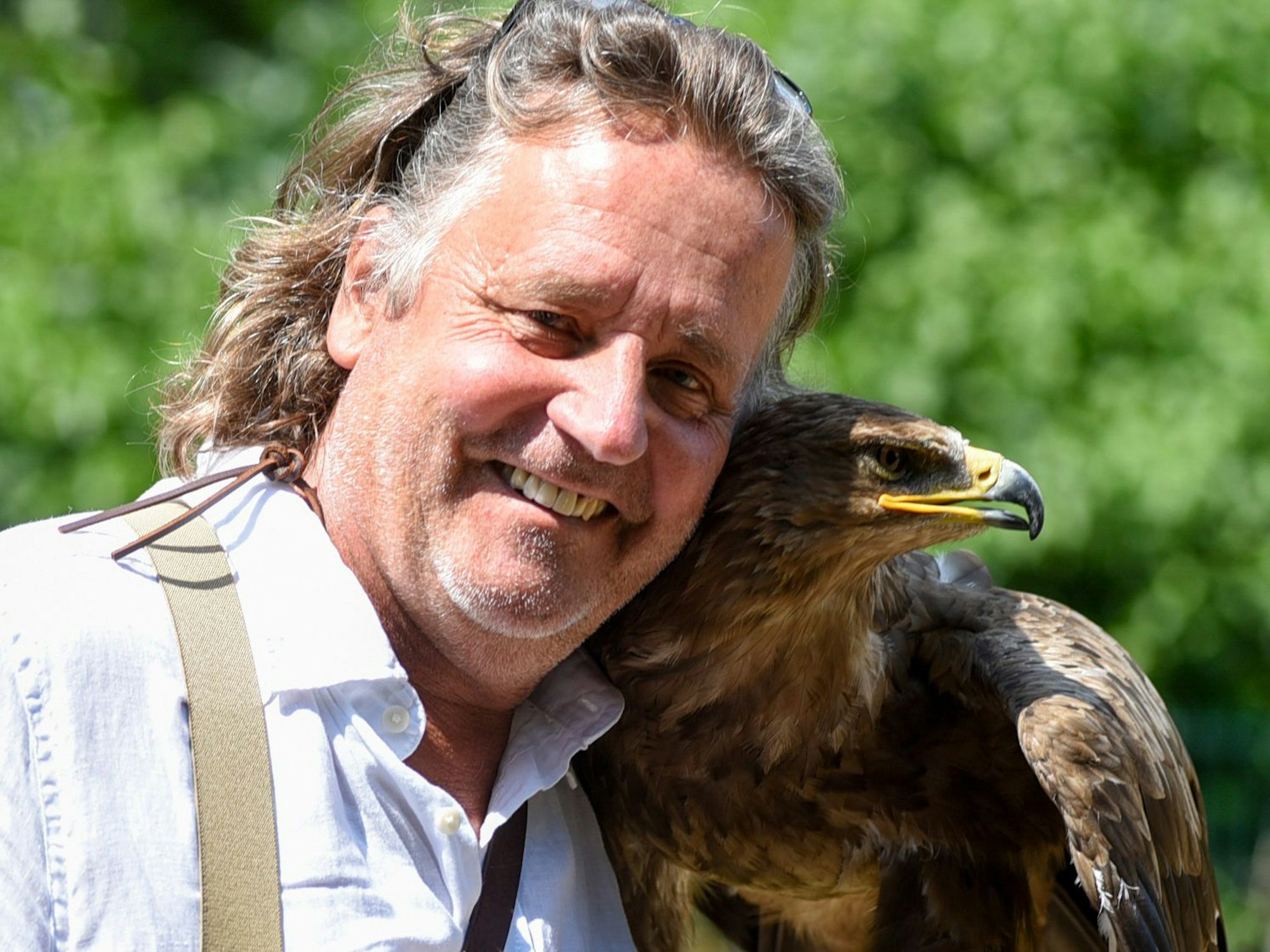 Ein Mann schaut lächelnd in Kamera, neben sich einen Adler.