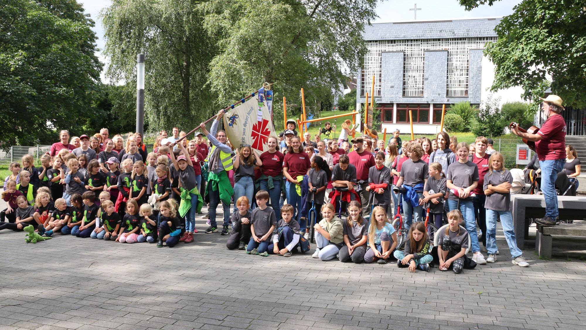 Die große Zirkusgruppe singt mit Gitarrenbegleitung.