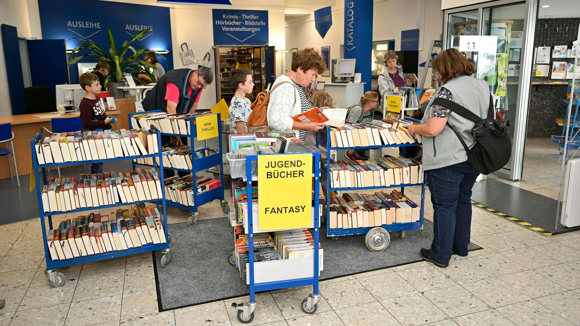 Menschen stöbern auf dem Medienflohmarkt in Büchern.