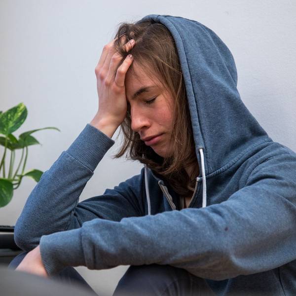 Eine junge Frau hält sich die Hand an den Kopf und guckt betrübt.