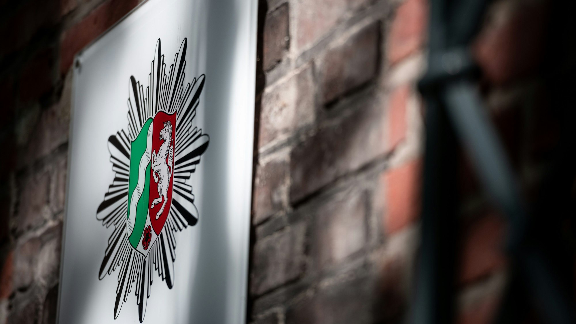 Das Wappen der Polizei Nordrhein-Westfalen hängt an der Wand eines Polizeipräsidium. Wegen illegaler Inhalte in Chats ist die Essener Staatsanwaltschaft am Mittwoch gegen Polizeibeamte in mehreren Behörden vorgegangen. Es seien Durchsuchungsbeschlüsse vollstreckt worden, teilte die Polizei Recklinghausen am Mittag mit.