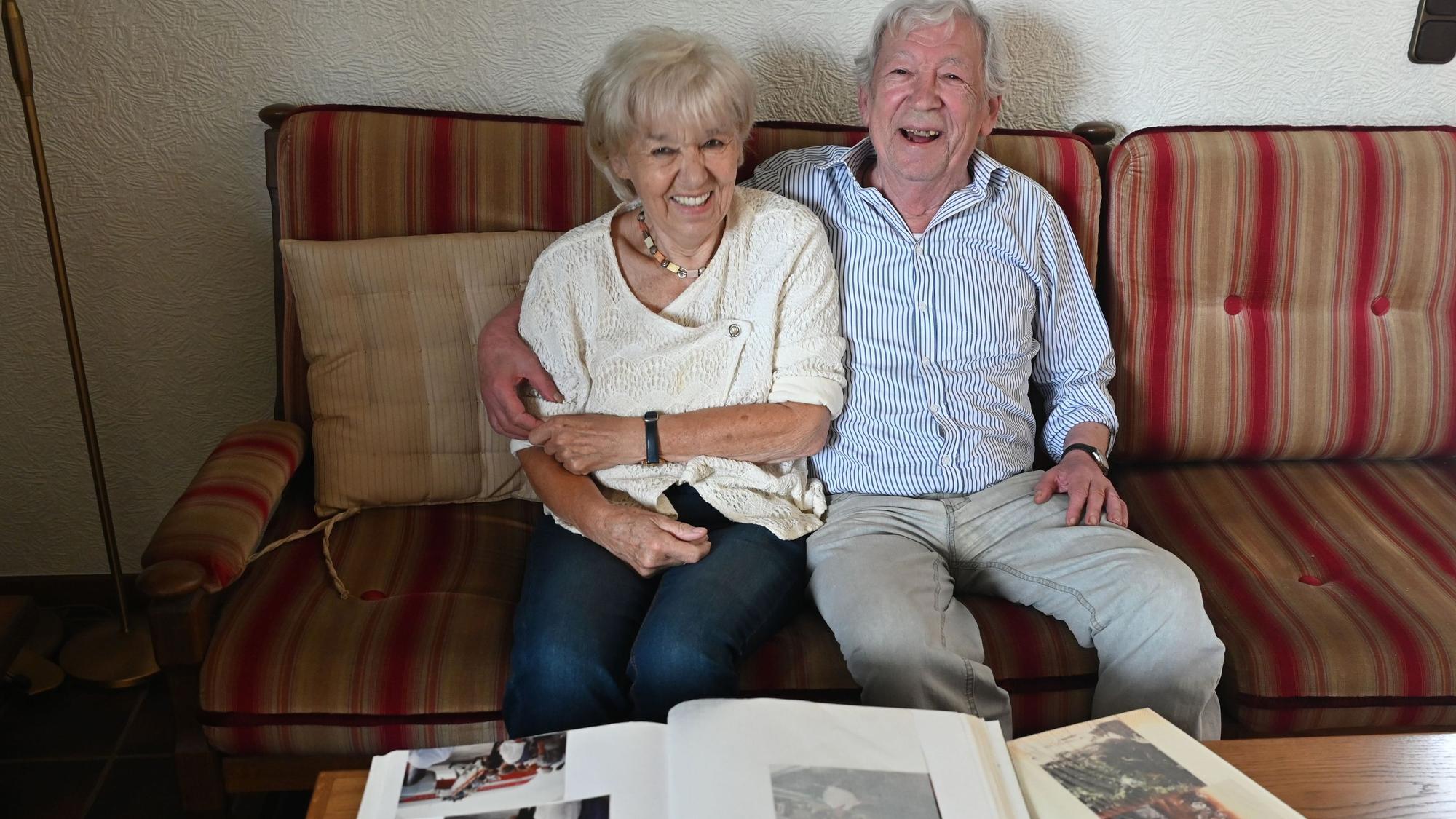 Das Goldpaar sitzt auf einem Sofa. Vor ihm auf dem Tisch liegen aufgeschlagene Fotoalben.