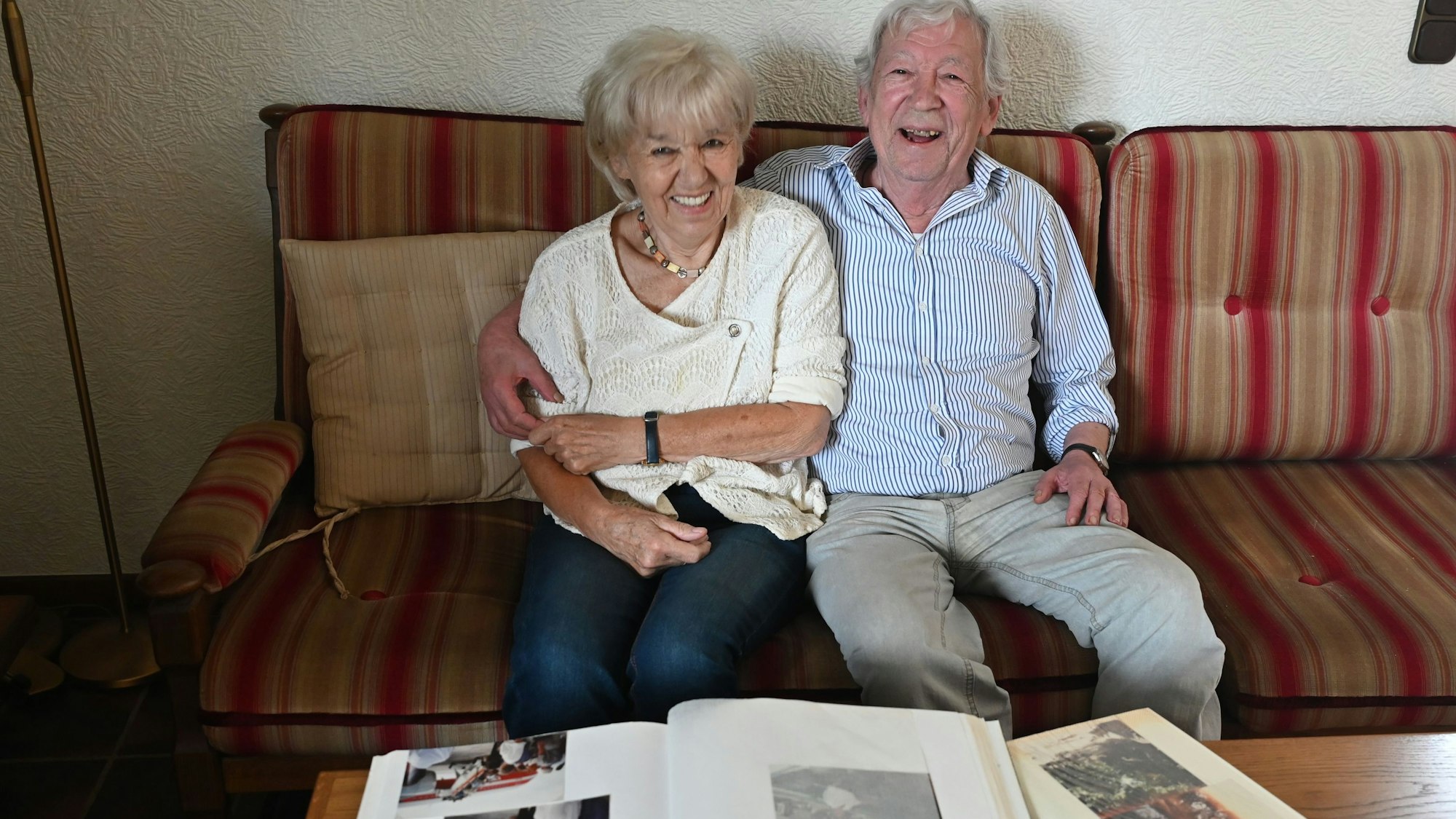 Das Goldpaar sitzt auf einem Sofa. Vor ihm auf dem Tisch liegen aufgeschlagene Fotoalben.