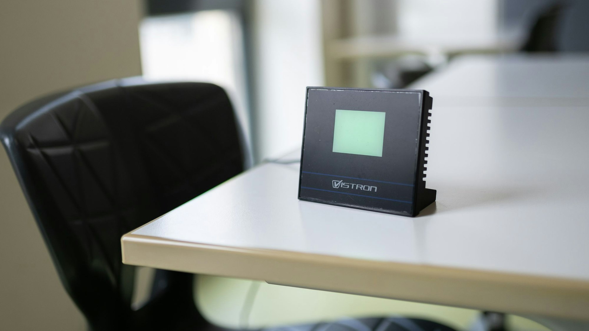 Ein schwarzes Messgerät mit leerer Anzeige steht auf einem Schultisch.