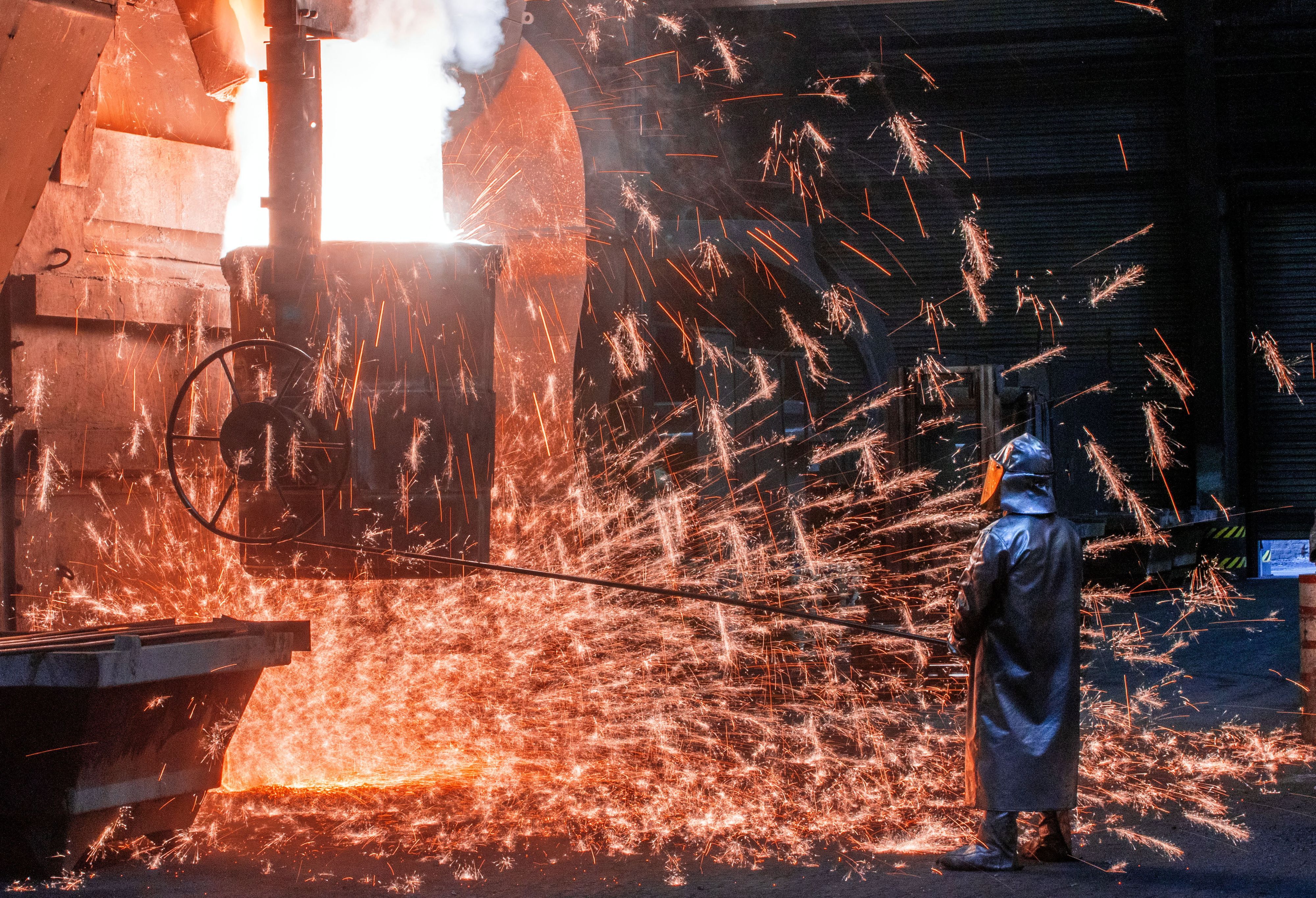 Ein Arbeiter mit Schutzmantel und Helm steht vor sprühenden Funken und kontrolliert die Abfüllungen in einen Transporttopf. Flüssiges Eisen mit einer Temperatur von 1.400 Grad wird in der Eisengießerei Torgelow für das Herstellen von großen Metallteilen vorbereitet. Die bis zu 110 Tonnen schwere Metallteile sind für Windkraftanlagen bestimmt. Die Corona-Krise belastet die Eisengießerei Torgelow GmbH in Vorpommern - einem der wichtigsten Industriebetriebe der Region und nach eigenen Angaben eine der größten Gießereien ihrer Art in Europa.