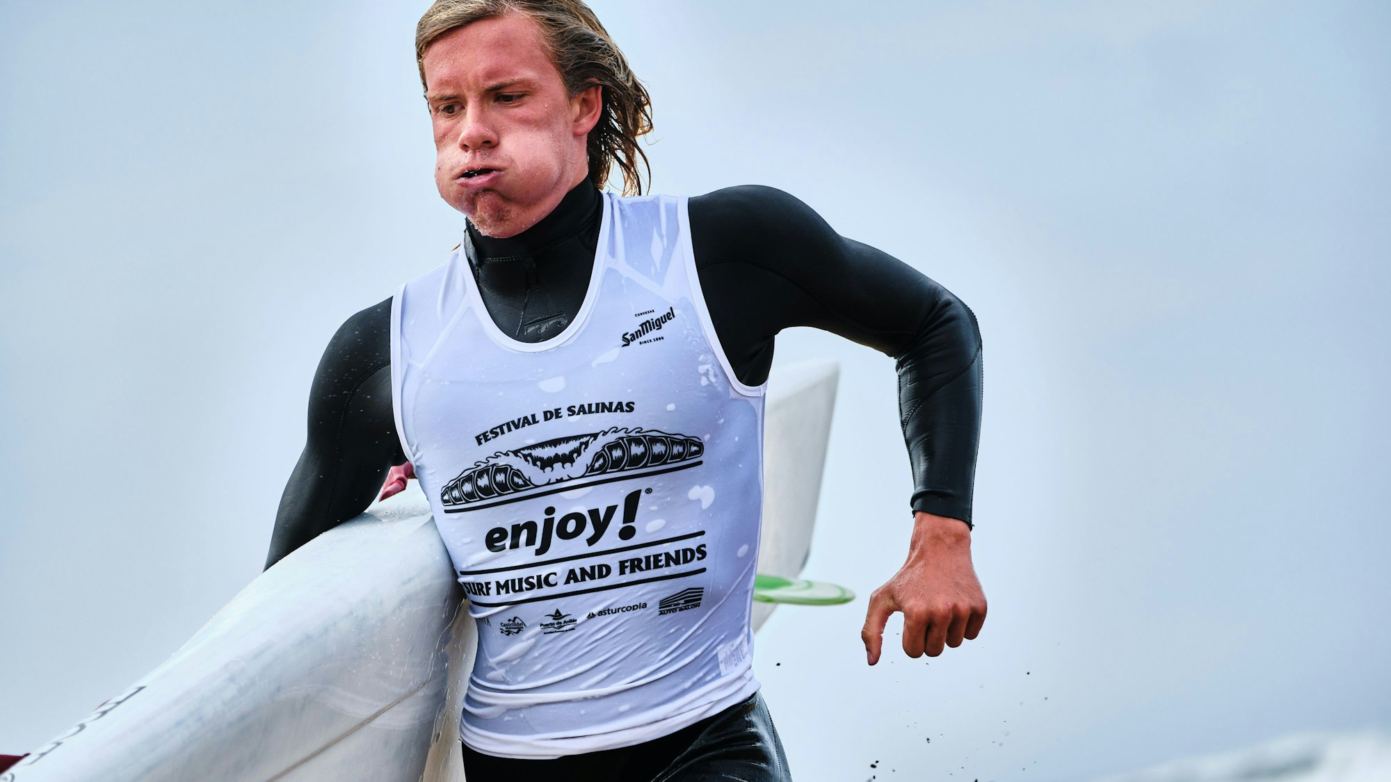 Auf dem Foto ist Lukas vom Eyser zu sehen. Er kommt gerade aus dem Wasser und trägt ein Board unter dem Arm.