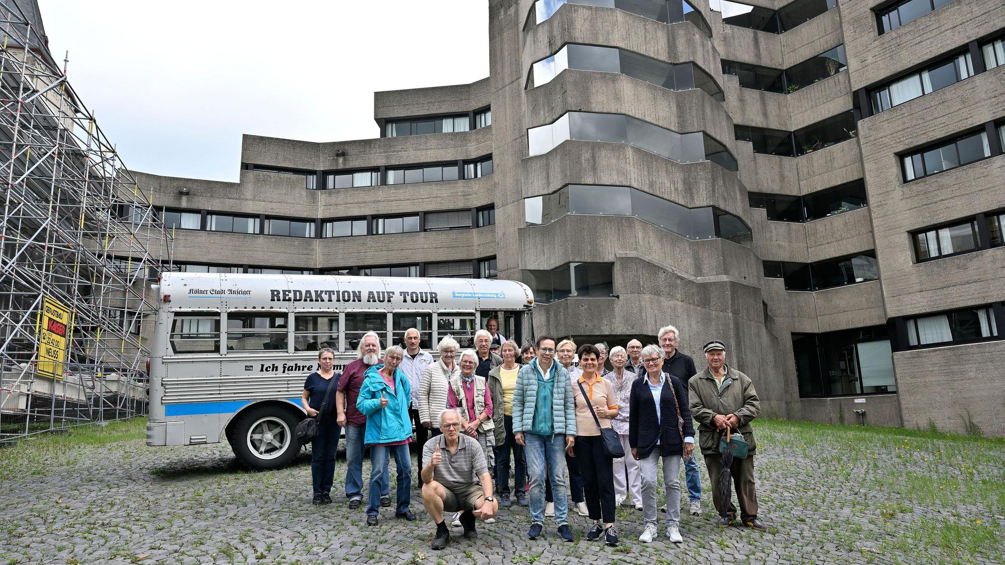 Eine Gruppe und ein historischer Bus stehen im Innenhof des Bensberger Rathauses.