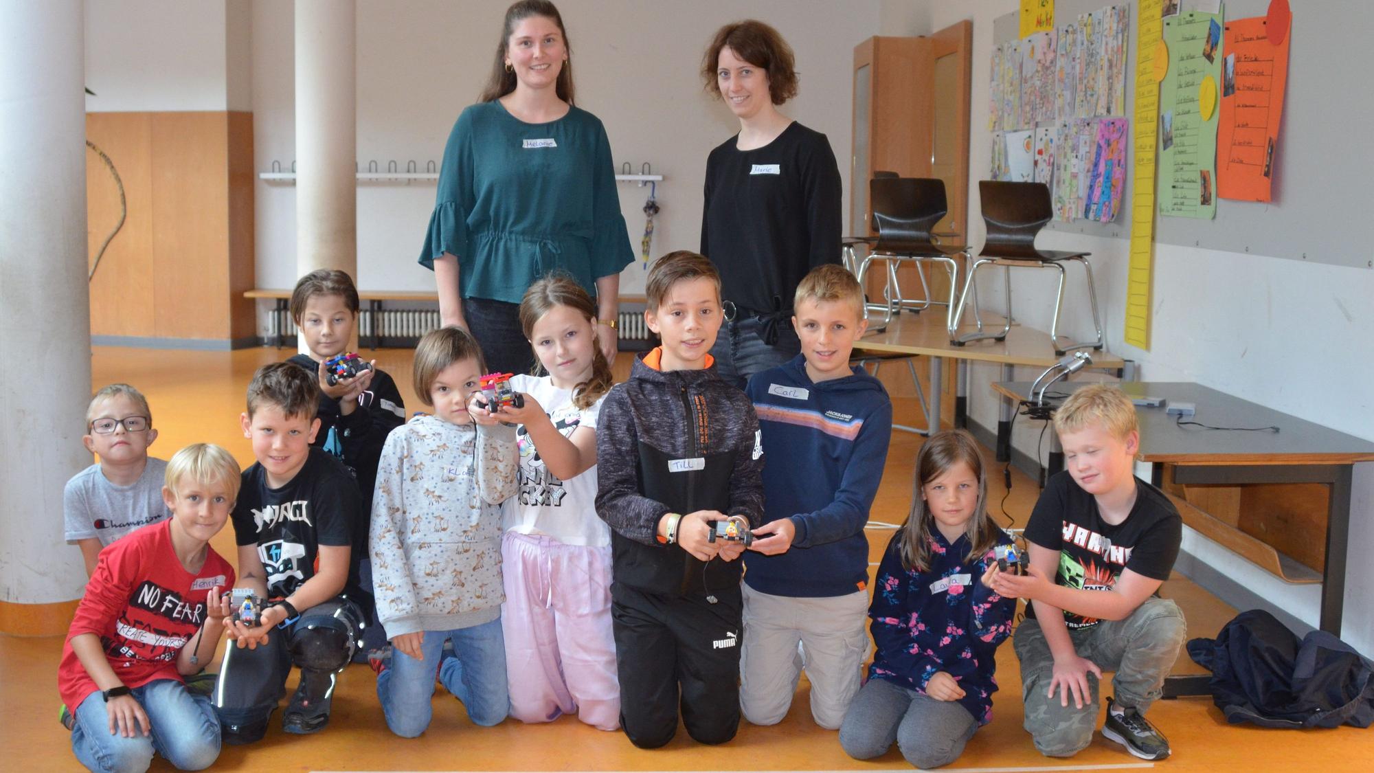 Mehrere Kinder präsentieren aus Legosteinen gebaute Gegenstände.