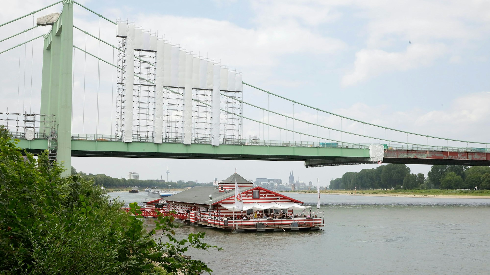 Das Bootshaus „Alte Liebe“ liegt an der Rodenkirchener Brücke im Rhein vor Anker.