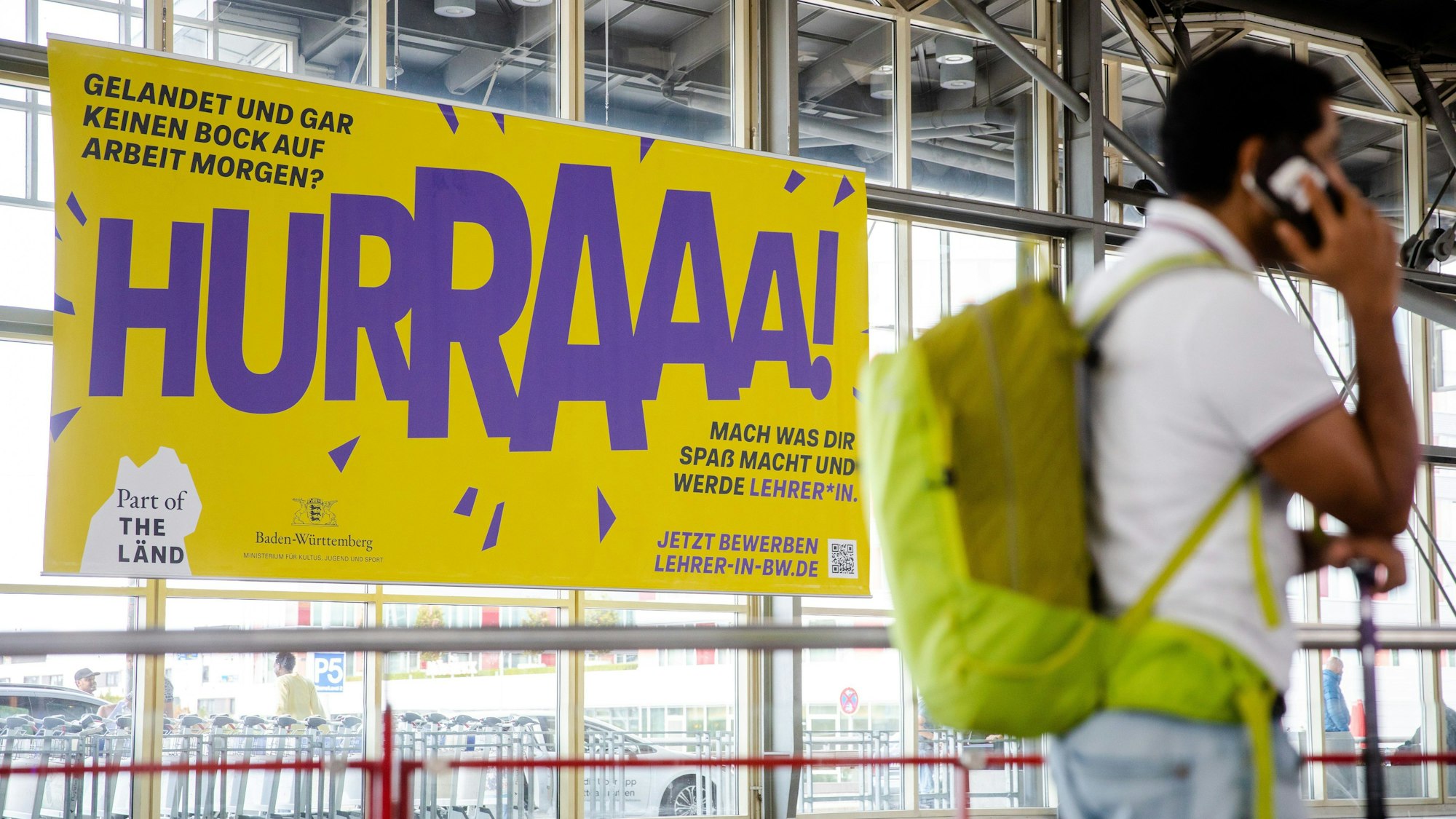 Ein Werbeplakat für den Beruf des Lehrers hängt am Flughafen in Stuttgart. An der Kampagnen gibt es scharfe Kritik.