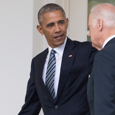 Barack Obama (l.) schaut Joe Biden (r.) an und hält seinen Arm hinter den Rücken des US-Präsidenten. Beide Männer tragen einen Anzug.