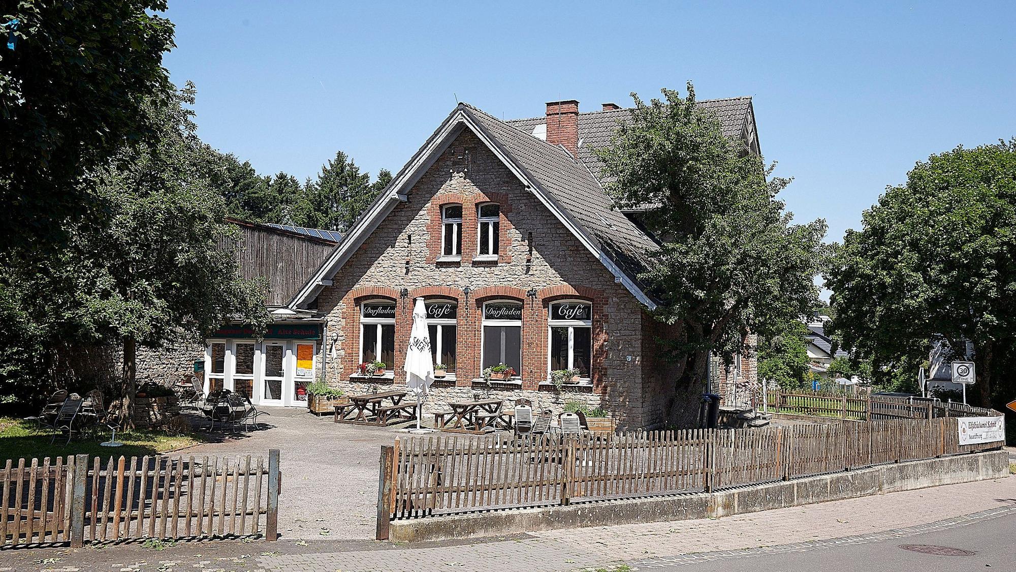 Das Foto zeigt den Dorftreff, der in der Alten Schule untergebracht ist. Davor ungenutzte Tische und Bänke.