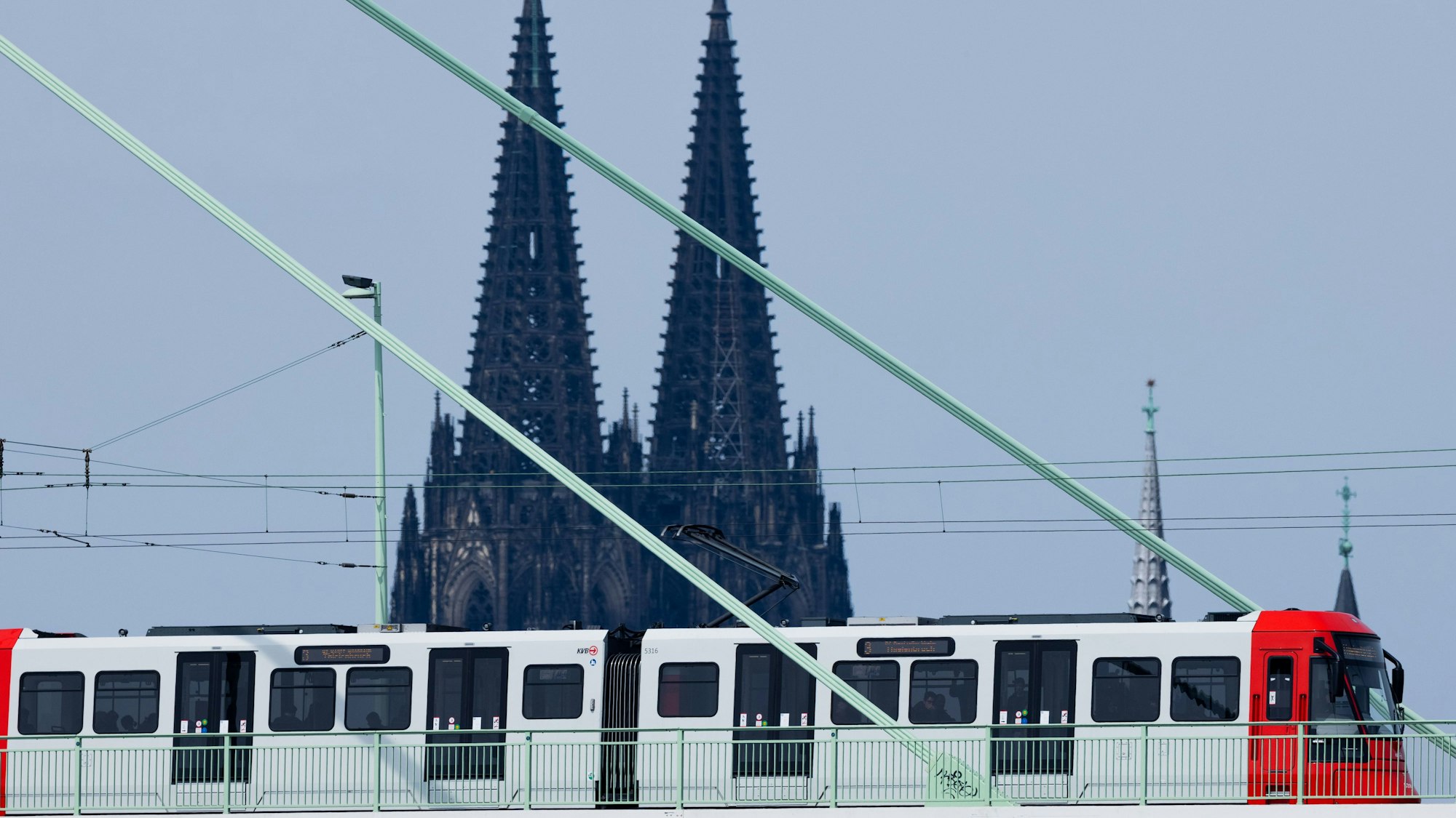 Eine Straßenbahn der Kölner Verkehrsbetriebe (KVB) fährt über die Severinsbrücke vor der Kulisse des Kölner Doms.