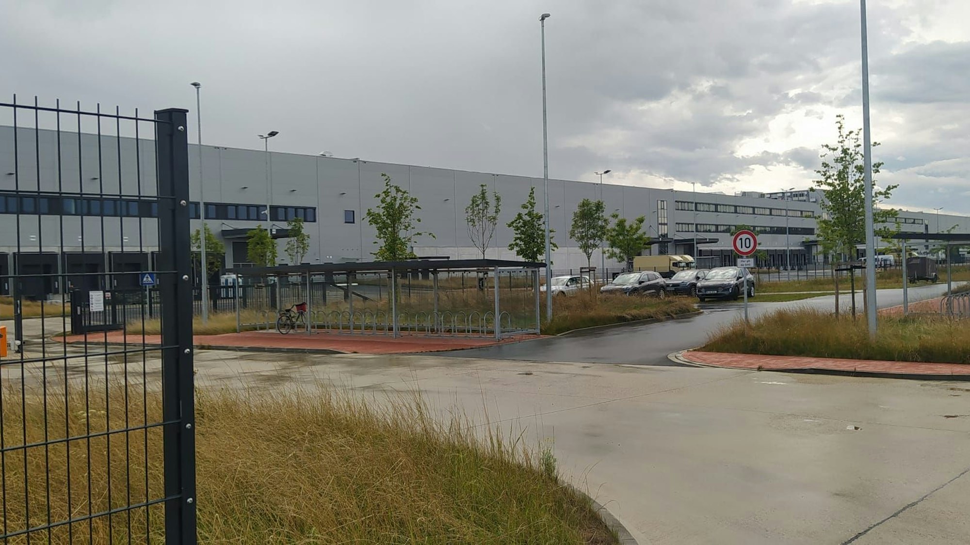 Junge Bäume stehen vor einem neuen, ganz in grau gehaltenen Industriegebäude.