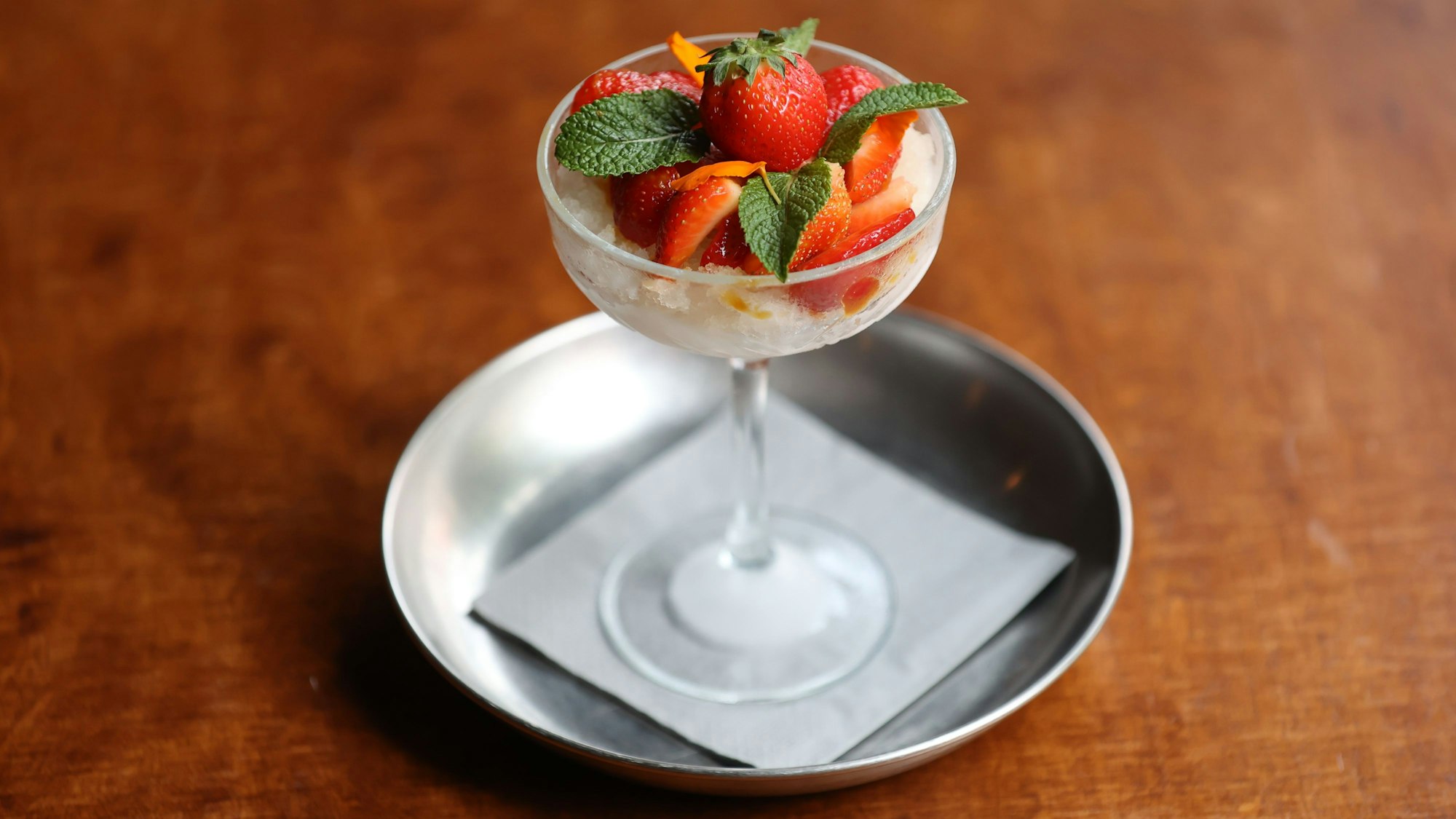 Mojito-Granita mit Erdbeeren serviert in einem hohen Glas.