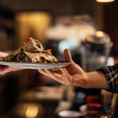 Ein Teller mit Essen wird in einem Restaurant übergeben