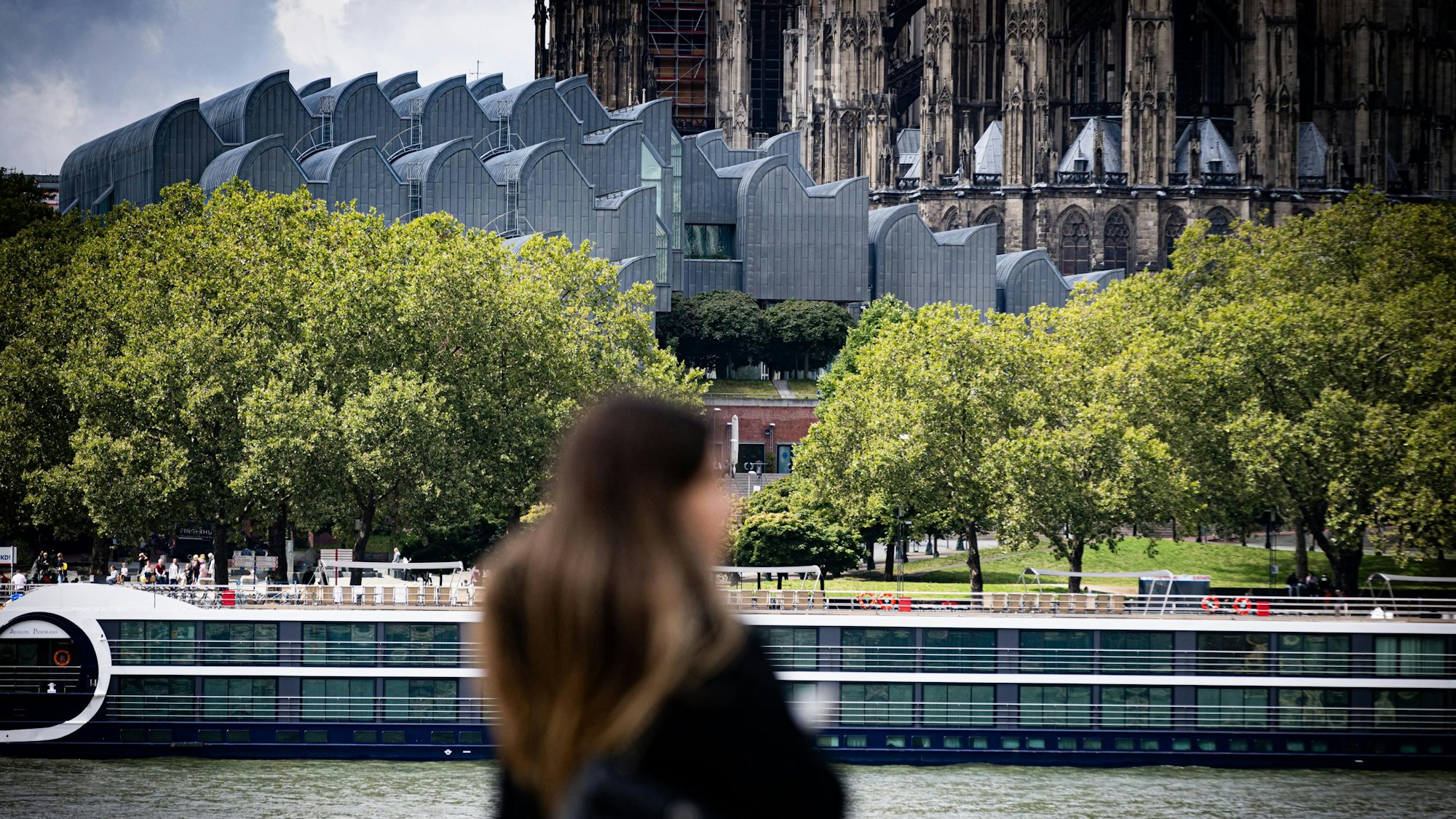 Eine Frau steht am Rhein mit Blick auf das Museum Ludwig.