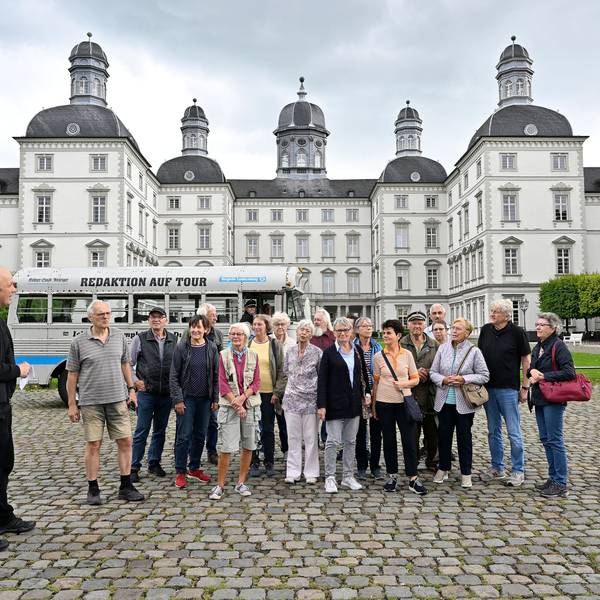 Eine Gruppe und ein historischer Bus stehen im Innenhof von Schloss Bensberg.