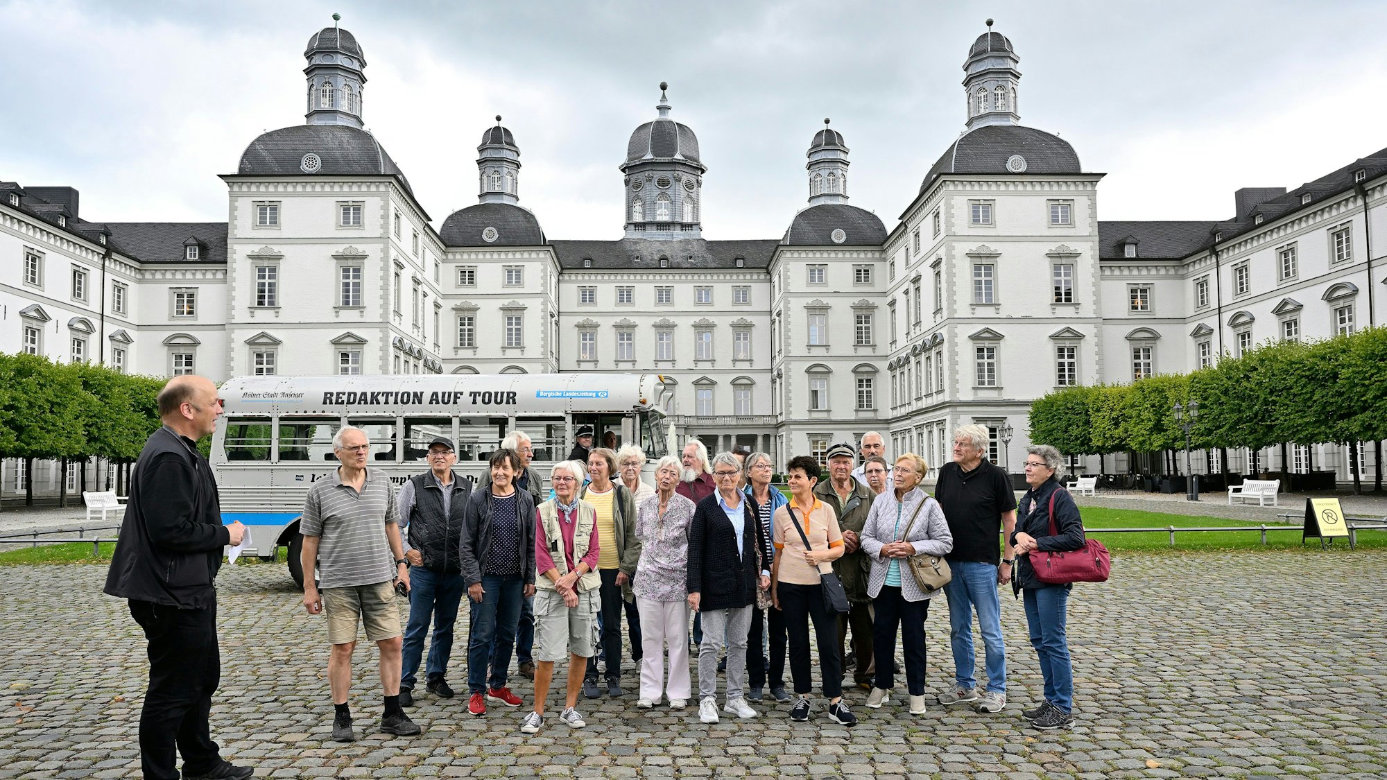 Eine Gruppe und ein historischer Bus stehen im Innenhof von Schloss Bensberg.