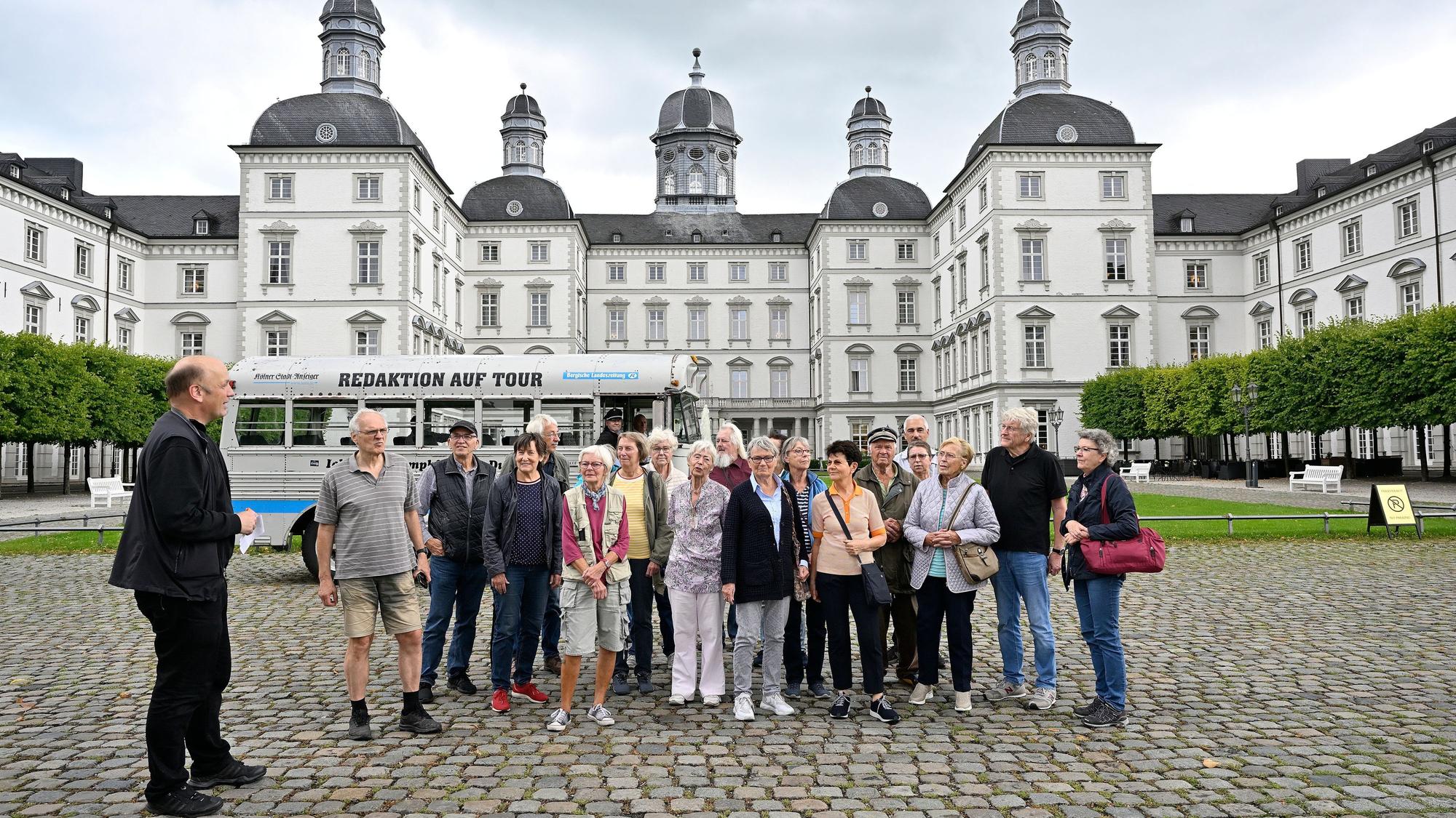 Eine Gruppe und ein historischer Bus stehen im Innenhof von Schloss Bensberg.