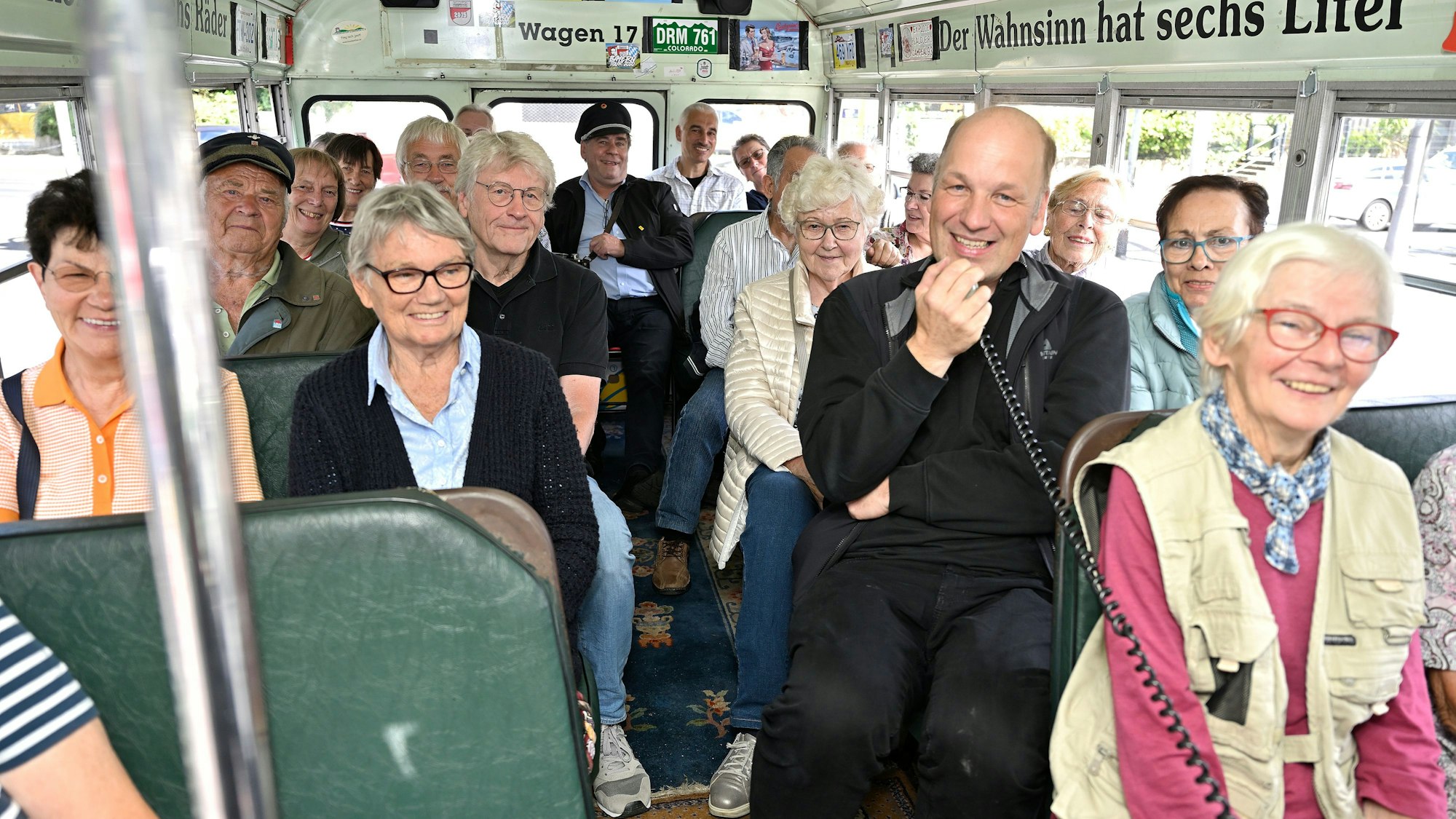 in einem historischen amerikanischen Schulbus sitzen Menschen, einer von ihnen spricht offenkundig in ein Mikrofon.