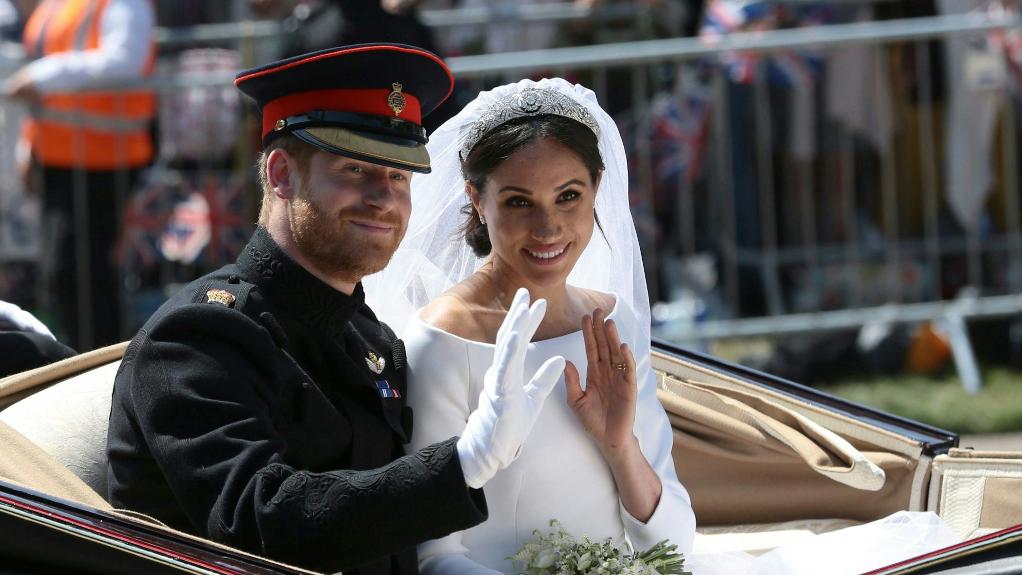 Bräutigam Prinz Harry und seine Braut Herzogin Meghan fahren nach ihrer Hochzeit in einer Kutsche und winken Menschen zu.