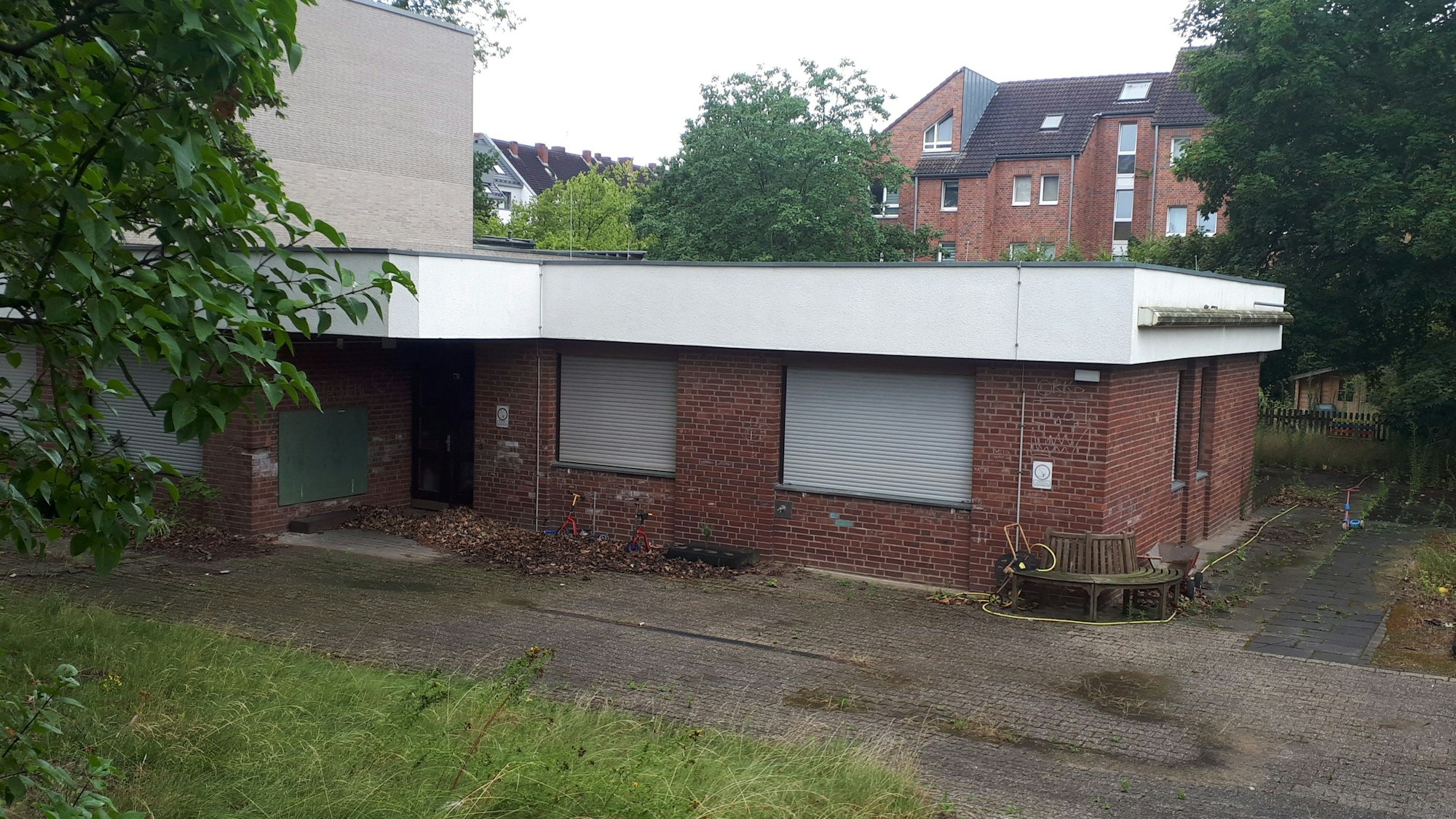 Ein Flachbau mit roten Klinkern und heruntergelassenen Rollläden ist zu sehen.