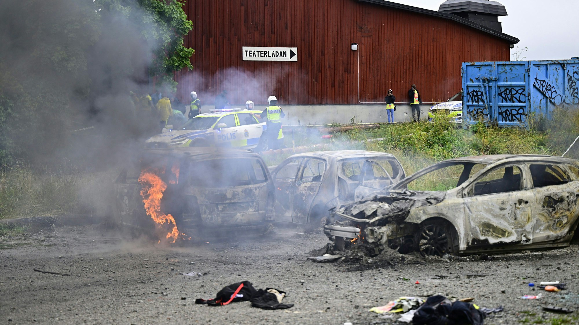 Polizisten stehen neben ausgebrannten Autos während des eritreischen Kulturfestivals „Eritrea Scandinavia“. Am Rande eines eritreischen Kulturfestivals ist es im Norden von Stockholm zu gewalttätigen Ausschreitungen gekommen.