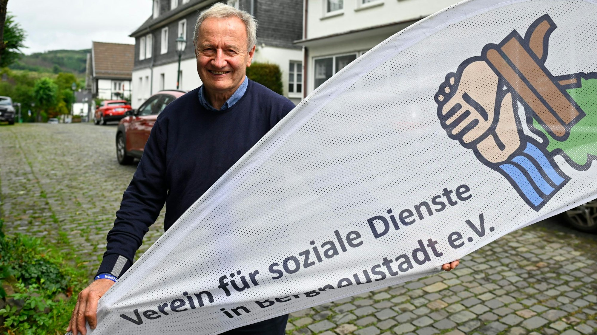 Friedhelm Julius Beucher hält ein Banner des Vereins für soziale Dienste in Bergneustadt in den Händen.