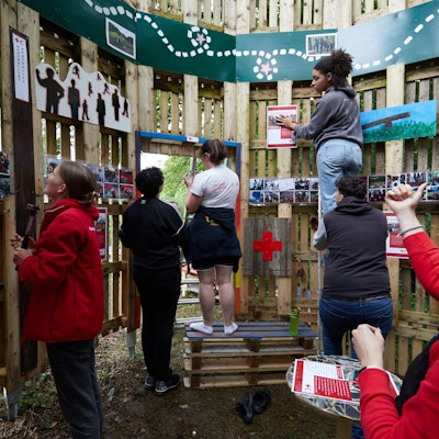 Junge Rotkreuzler verzieren Bretterwände mit Bildern.