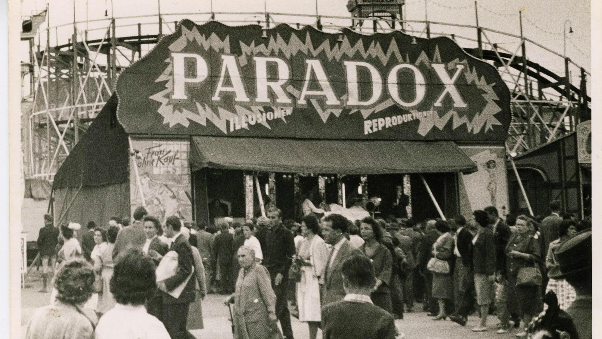 Ein altes Foto in Schwarz-Weiß zeigt eine Schaubude auf einem Jahrmarkt.
