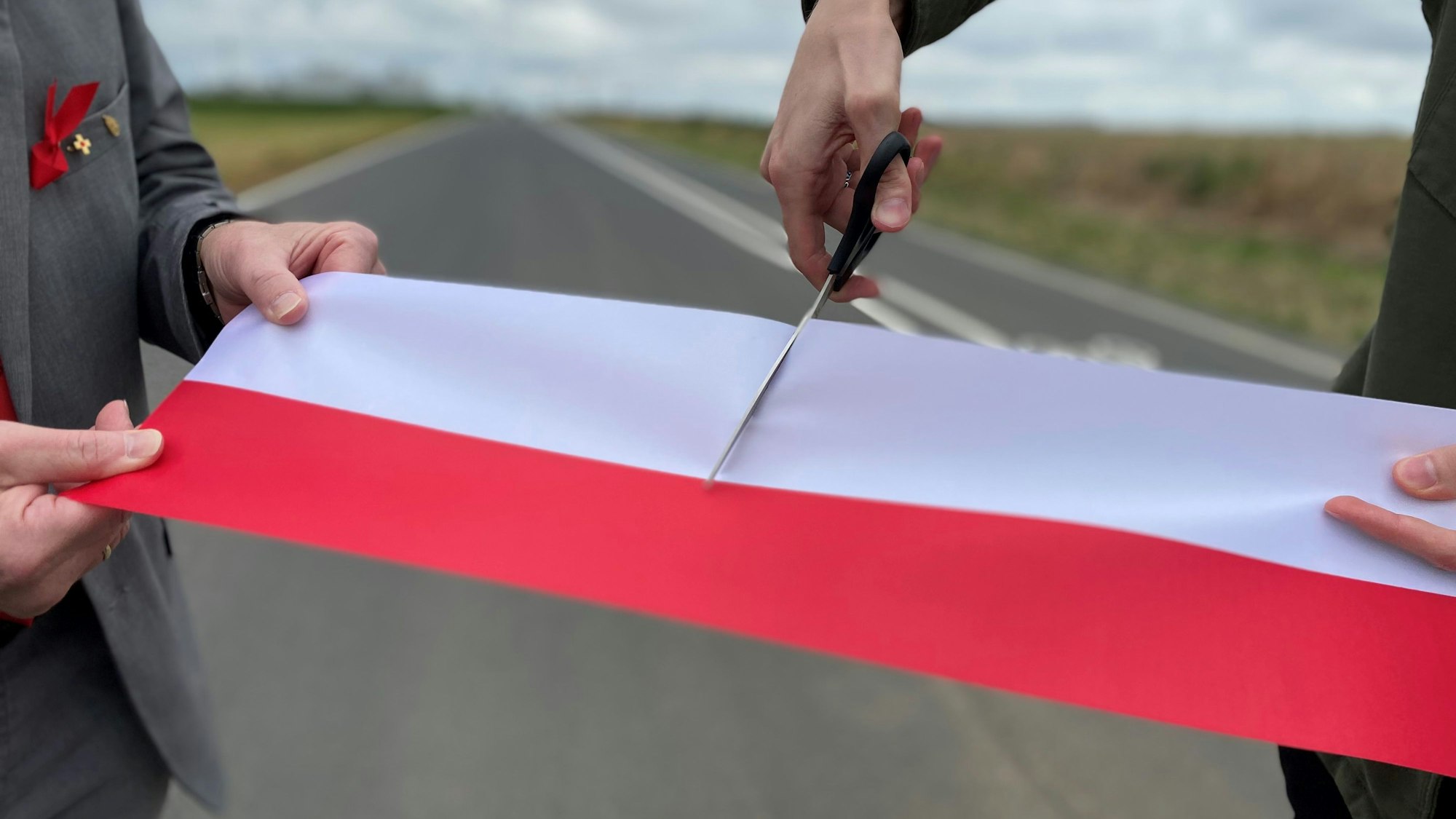 Das Bild zeigt den symbolischen Akt der Freigabe. Ein rot-weißes Band wird mit einer Schere durchgeschnitten.