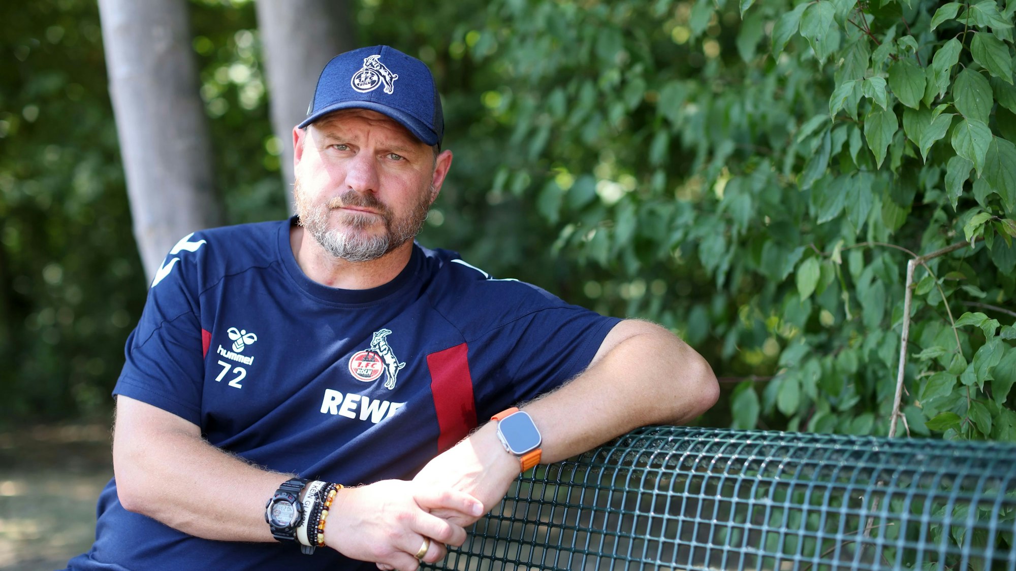 Steffen Baumgart, Trainer des 1. FC Köln, sitzt auf einer Bank am Geißbockheim.