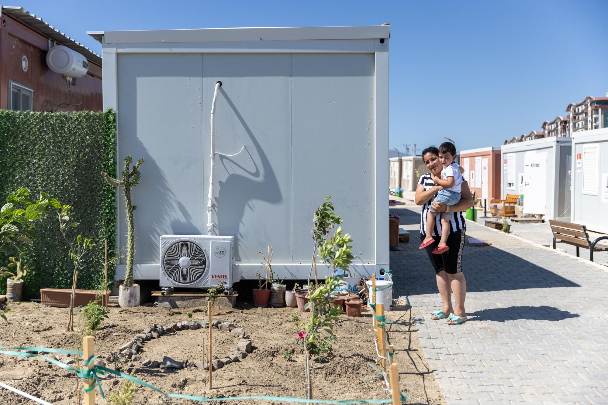 Derman Demirkol (37) und ihr Sohn stehen vor einem Schiffscontainer im ‚Katar-Containerlager‘, in dem sie derzeit leben. Ihr Haus wurde bei dem Erdbeben vor fast sechs Monaten zerstört.