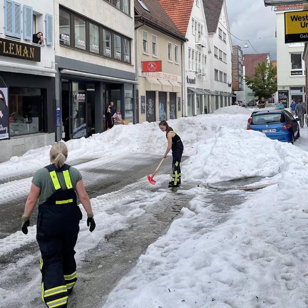 04.08.2023, Baden-Württemberg, Reutlingen: Einsatzkräfte der Feuerwehr räumen Hagel von einer Straße. Winterdienst-Einsatz mitten im Sommer: Ein lokal begrenztes Unwetter hat Straßen in der Innenstadt von Reutlingen mit einer hohen Hagel-Schicht überzogen. Foto: Schulz/SDMG/dpa +++ dpa-Bildfunk +++
