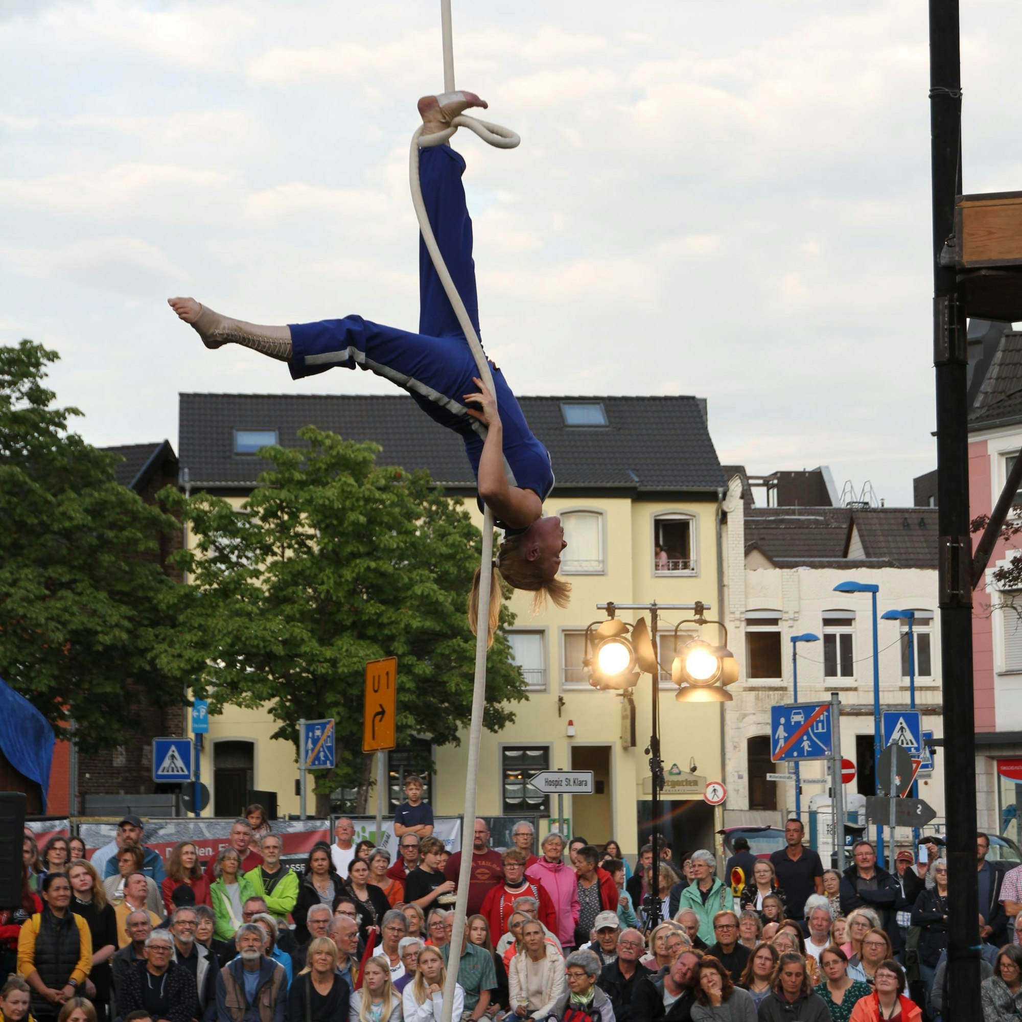 Eine Artistin schwebt an einem Seil hoch über dem Publikum.