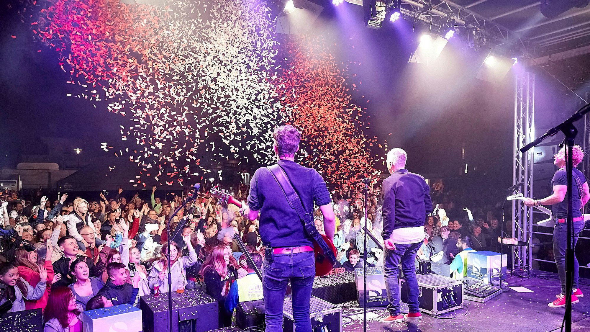 Das Bild zeigt von hinten Musiker der Kölner Band Kasalla. Aus einer Kanone wird rot-weißes Konfetti auf die Zuschauer geschossen.
