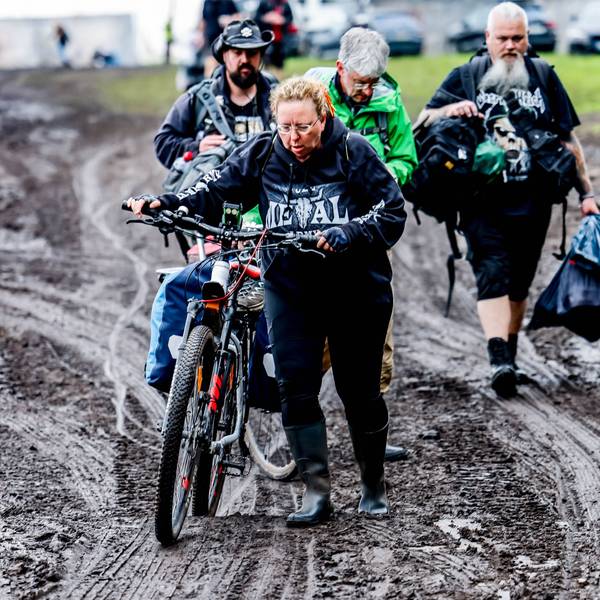 06.08.2023, Schleswig-Holstein, Wacken: Festivalbesucher verlassen das verschlammte Campinggelände des Wacken Open Air mit ihren Fahrrädern. Foto: Axel Heimken/dpa +++ dpa-Bildfunk +++