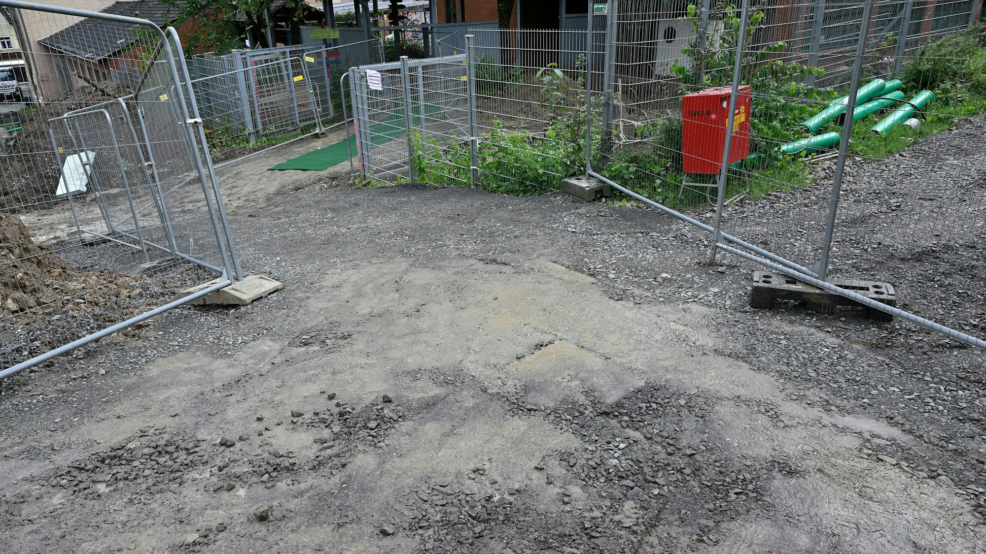 Absperrgitter säumen einen schlammigen Weg, den die Kinder nutzen müssen.