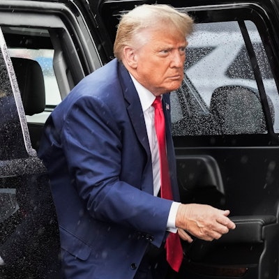 Der ehemalige US-Präsident Donald Trump steigt aus einem verregneten, schwarzen Auto.