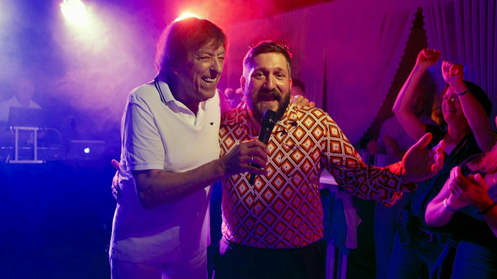 Zwei Männer stehen auf einer Bühne und singen.