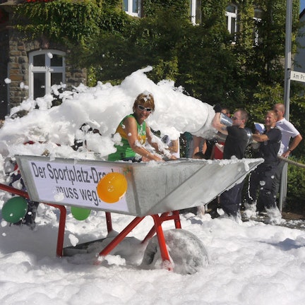Eine überdimensionale Schubkarre rollt während des Schubkarrenrennens in Morsbach am Rathaus der Gemeinde vorbei.