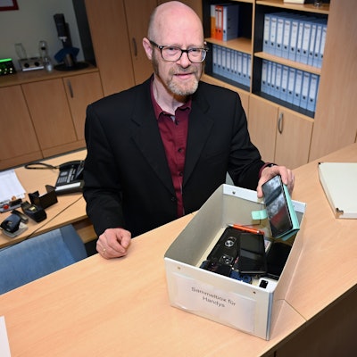Frank Bohlscheid, Direktor des Hollenberg-Gymnasiums in Waldbröl, steht im Schulsekretariat. Vor ihm auf dem Tresen befindet sich eine Kiste: Dies ist das „Handy-Hotel“, in dem Mobiltelefone von Schülerinnen und Schülern gesammelt werden, die Lehrkräfte zuvor einkassiert haben.