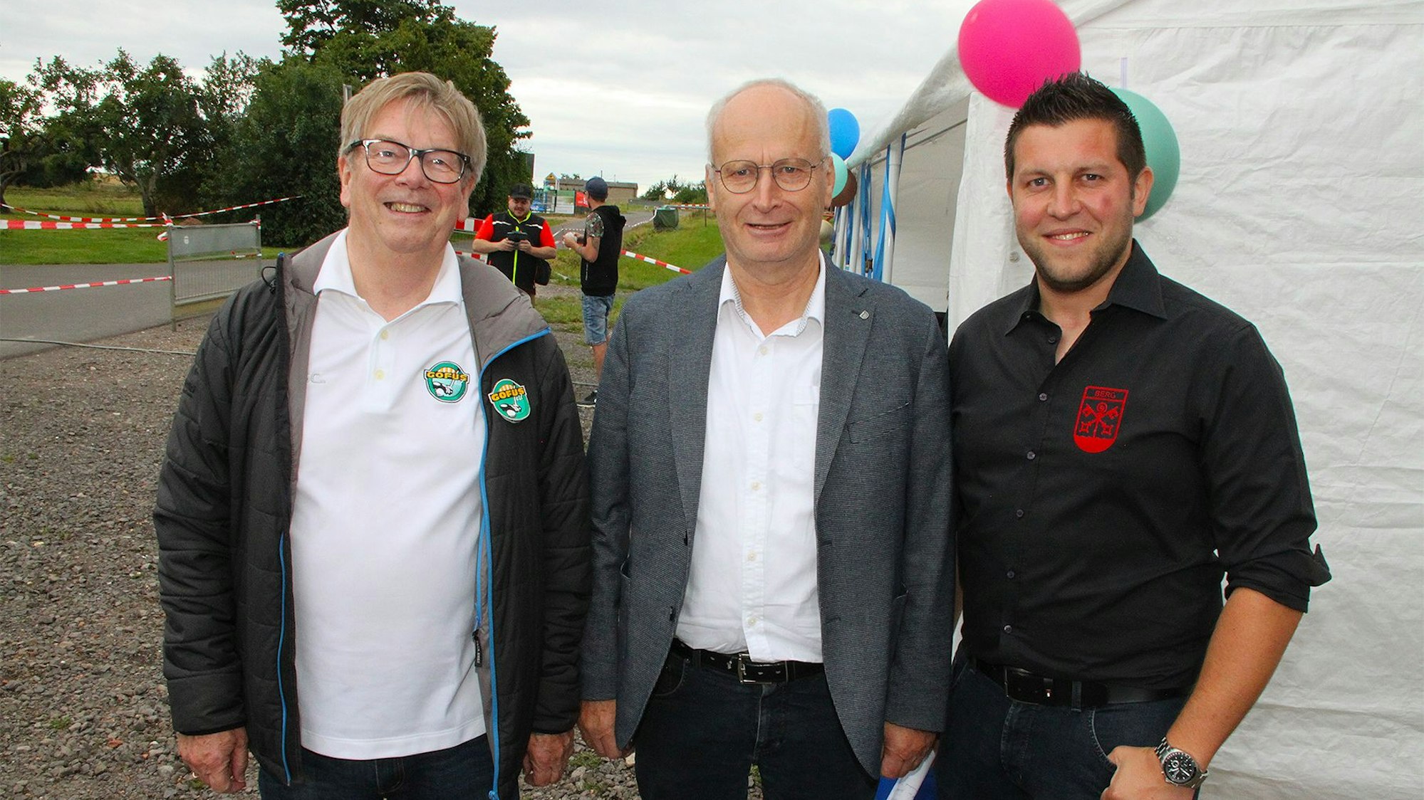 Friedhelm Bröker, Hans-Peter Schick und Stefan Schmitz stehen vor einem mit Luftballons geschmückten Zelt.