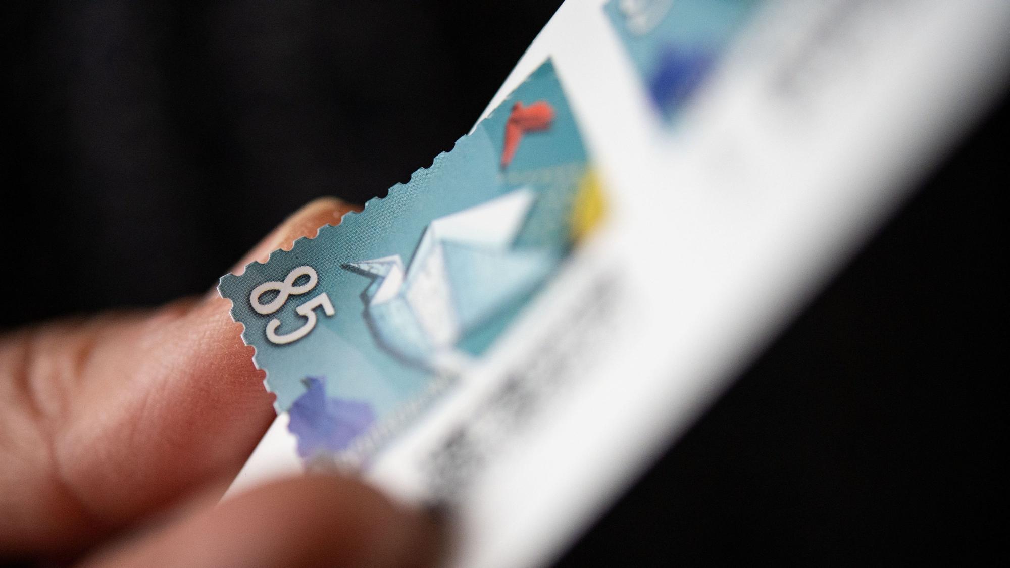 Eine Frau löst eine 85 Cent Briefmarke von einem Bogen. (Symbolbild)