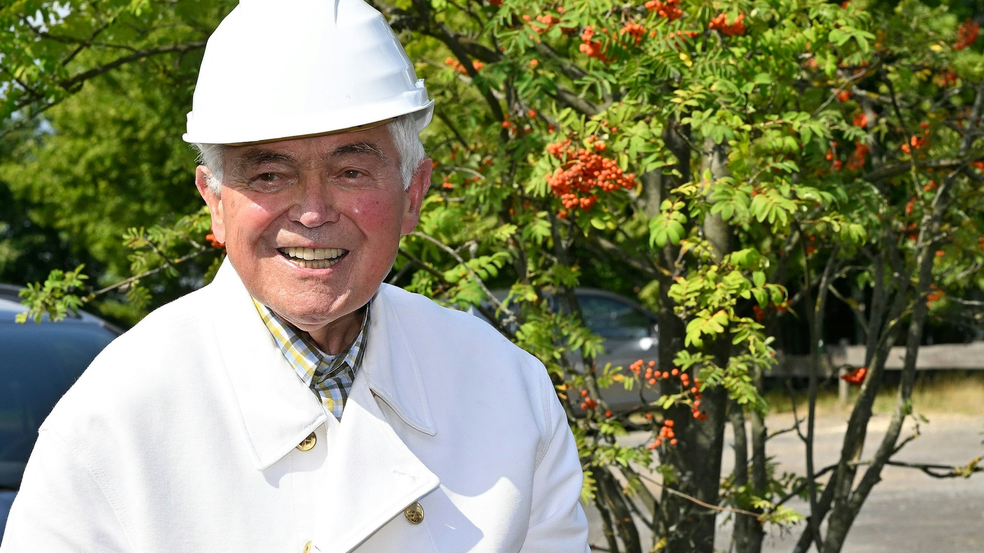 Sigfried Reimann steht am Bergbaurevier auf dem Lüderich und trägt einen weißen Bergmannshelm.