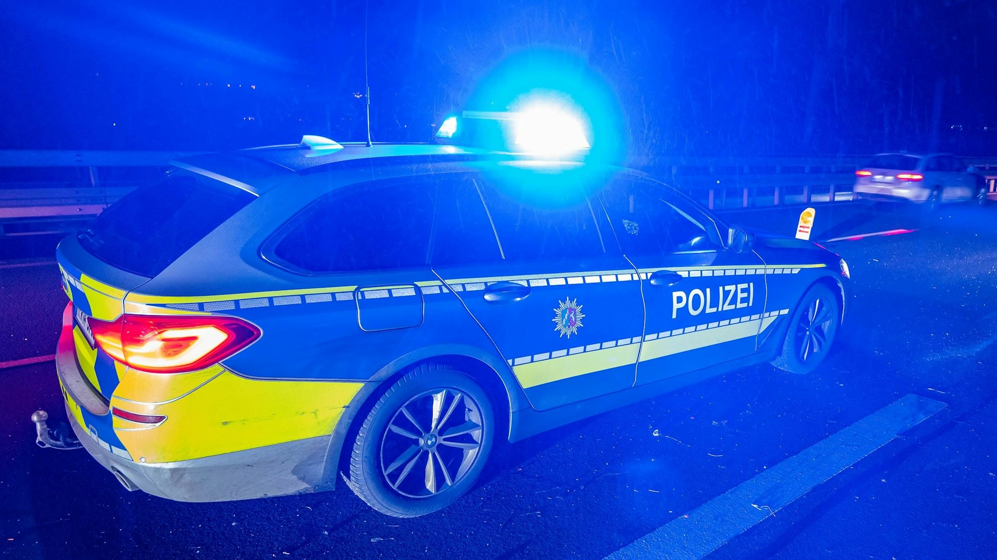 Ein Einsatzfahrzeug der Oberbergischen Kreispolizei steht mit eingeschaltetem Blaulicht auf einer nächtlichen Straße.