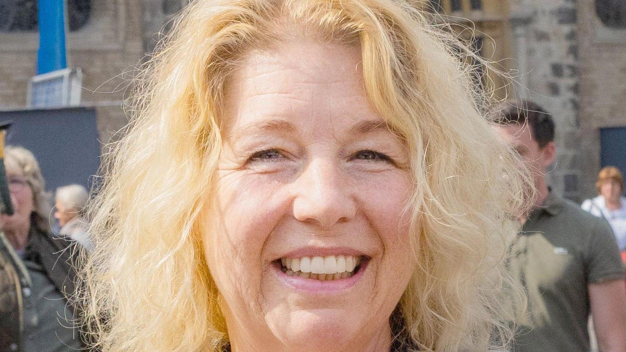 Eine Frau mit blonden Haaren lächelt in die Kamera.