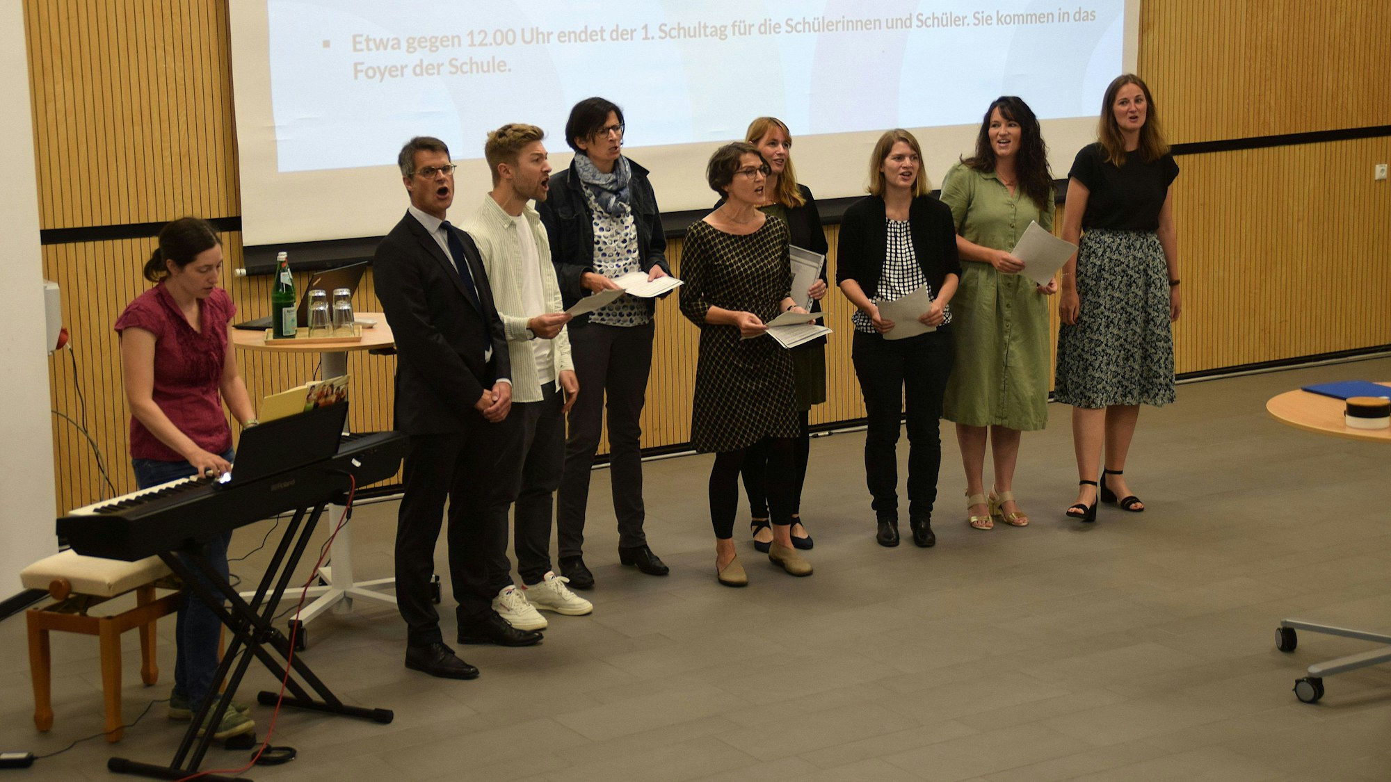 7. August 2023. Alfter-Oedekoven. Mit einer Feierstunde in der Aula ging das neu gegründete Gymnasium der Gemeinde Alfter an den Start. Das Lehrerkollegium und Schulleiter Sebastian Muders (2. von links) sangen "Probier's mal mit Gemütlichkeit". Foto: Frank Engel-Strebel