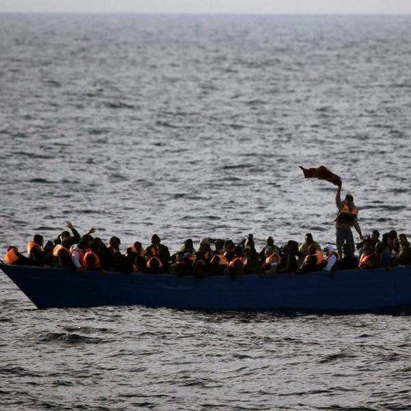 Geflüchtete aus Afrika rufen auf dem Mittelmeer in einem Boot um Hilfe.